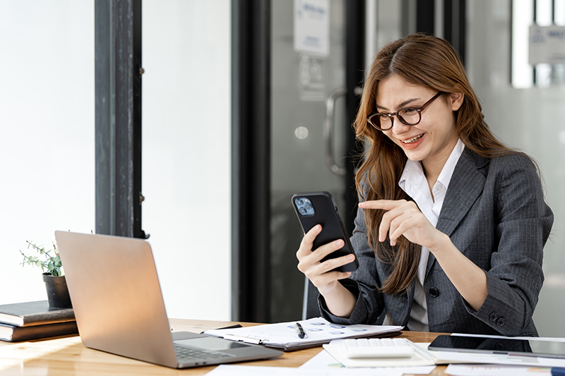 Young beautiful woman using mobile phone in modern office Cute